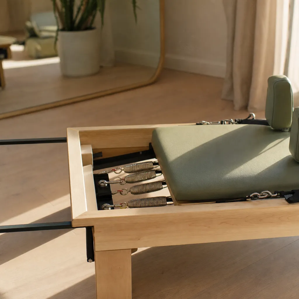 Close detail of a reformer carriage, springs and straps in soft light